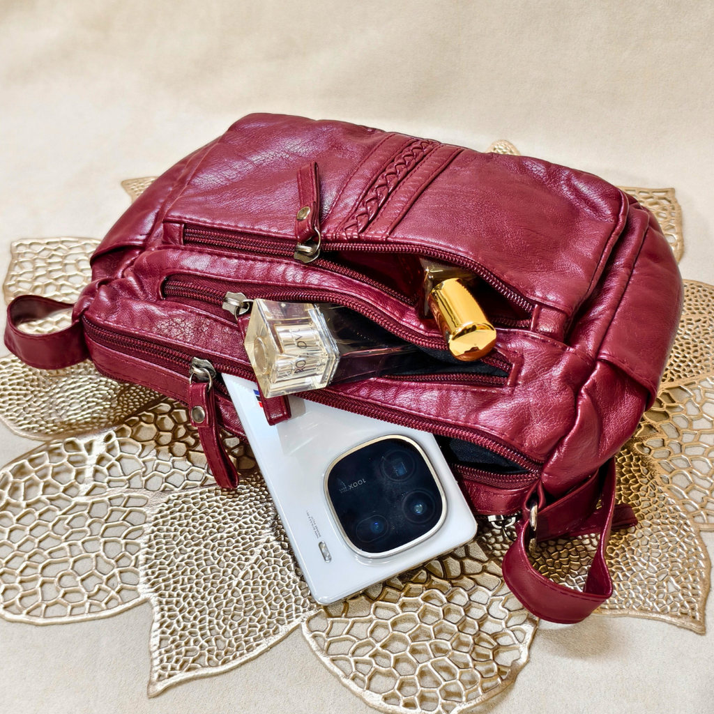 Red leather bag with a phone and perfume bottle on a textured surface