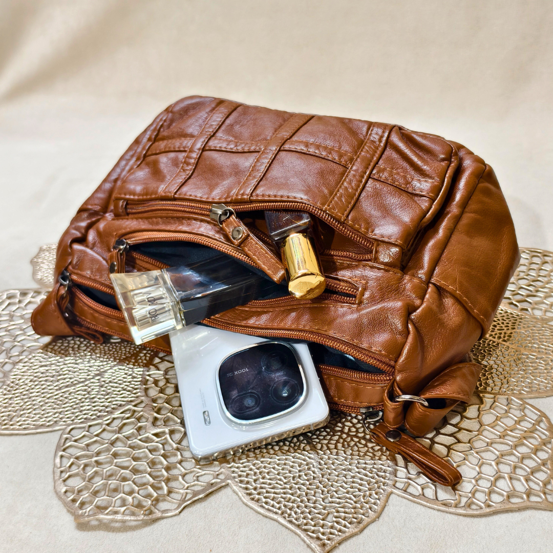 Brown leather clutch bag with items on a textured surface