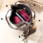 Open beige handbag with pink pouch and notebook on a beige background