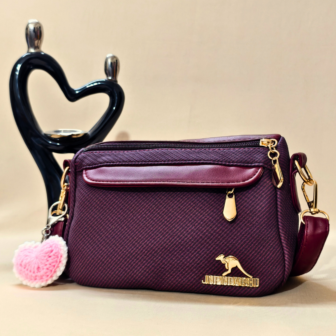 Purple handbag with gold accents and a pink heart charm on a beige background