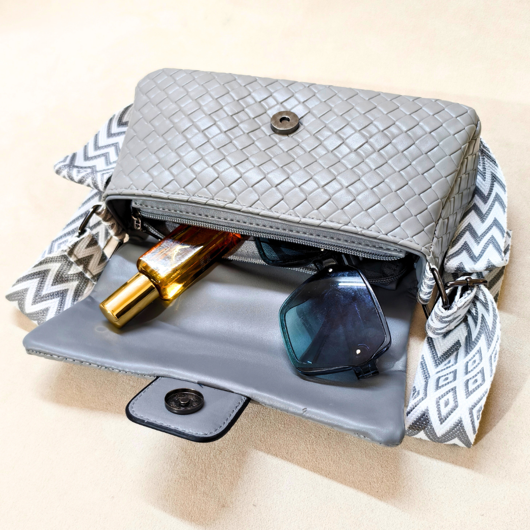 Gray woven handbag with sunglasses and a bottle on a beige background