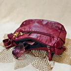 Red leather bag on a textured surface with a beige background