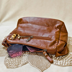 Brown leather bag with sunglasses on a textured surface