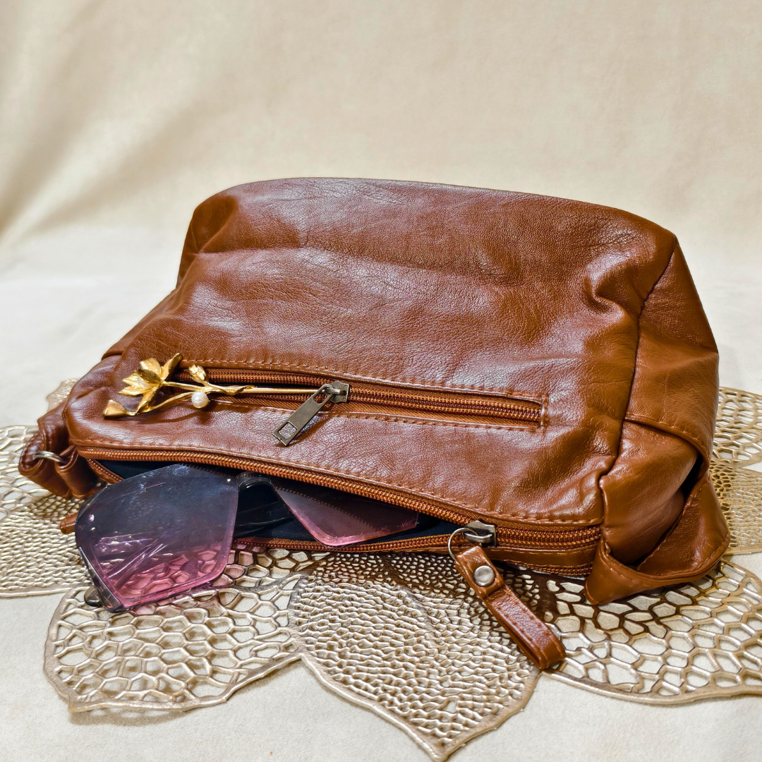 Brown leather bag with sunglasses on a textured surface