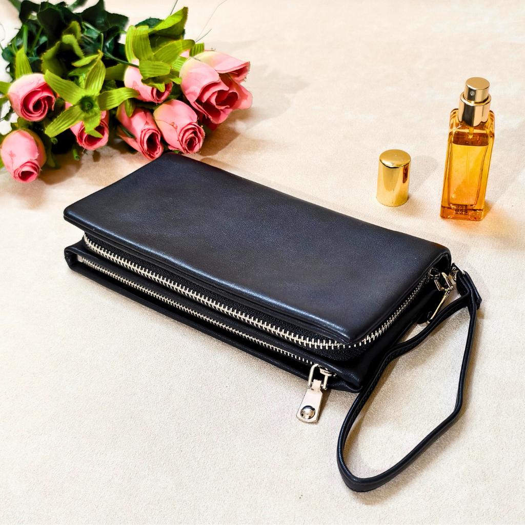 Black leather wallet with floral arrangement and perfume bottle on a light surface