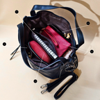 Black handbag with a pink wallet inside on a beige background
