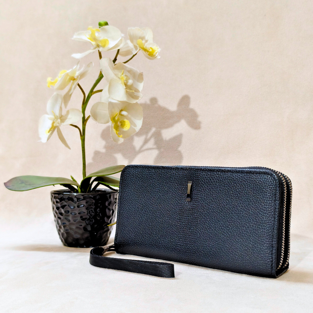 Black leather wallet with a potted orchid on a light background