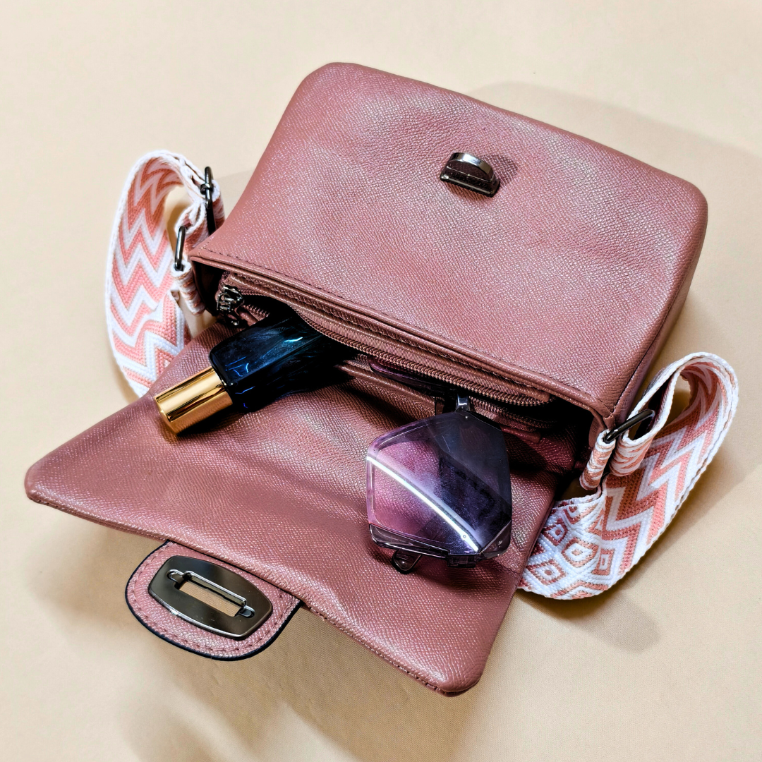 Pink handbag with cosmetic items on a beige background