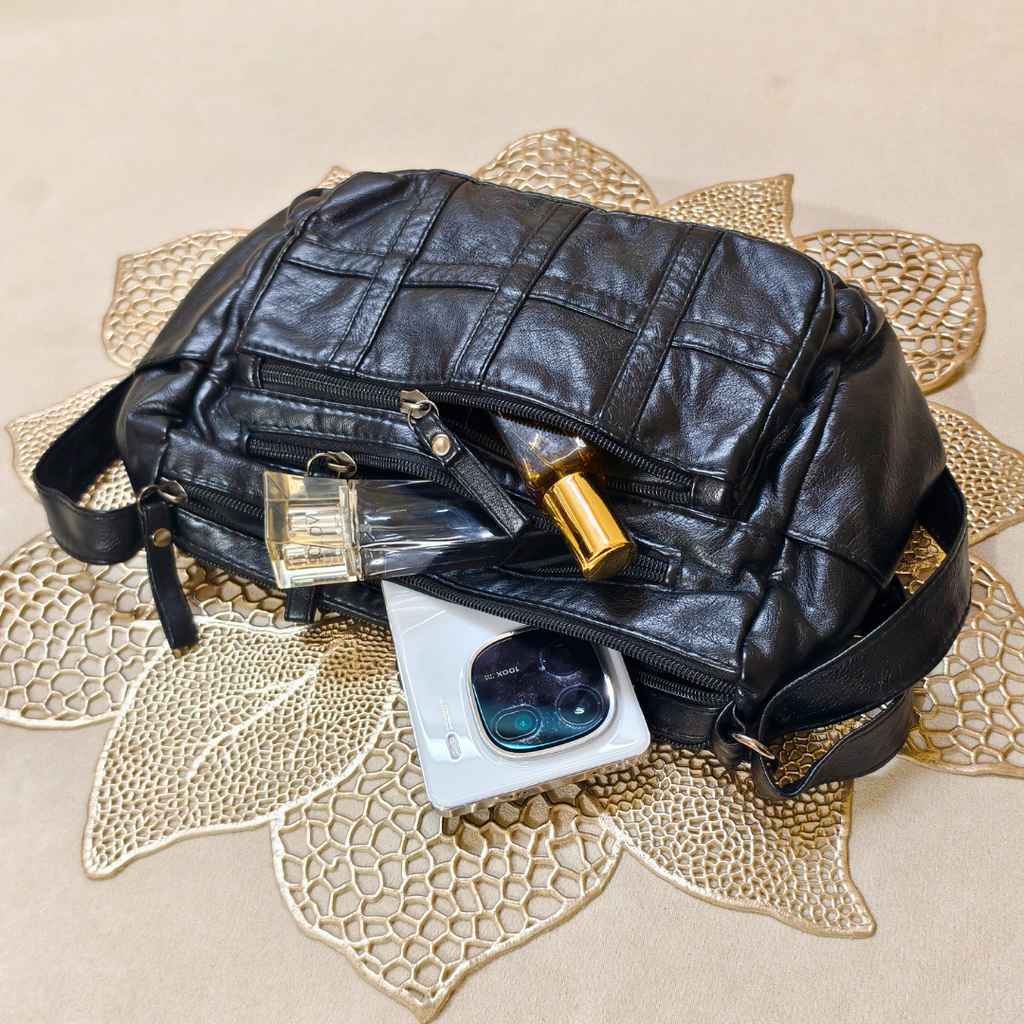 Black leather bag with a phone and sunglasses on a decorative mat