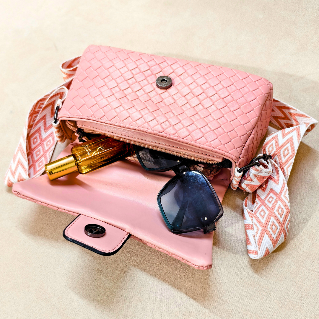 Pink woven handbag with sunglasses and a bottle on a beige background