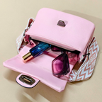 Pink handbag with sunglasses and a bottle on a beige background