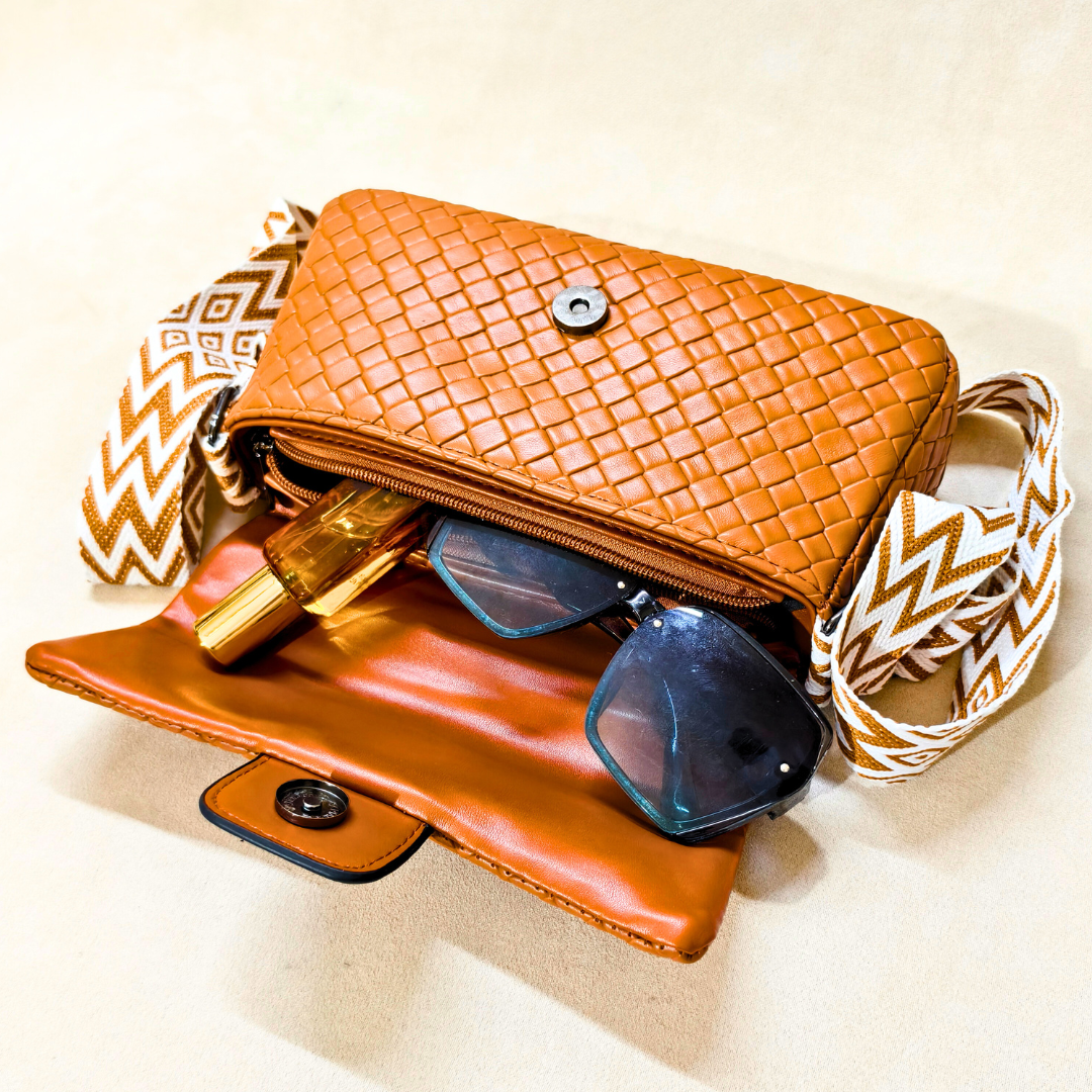 Brown woven handbag with sunglasses and a gold item on a beige background