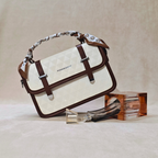 White handbag with brown accents and a scarf, next to perfume bottles on a beige background