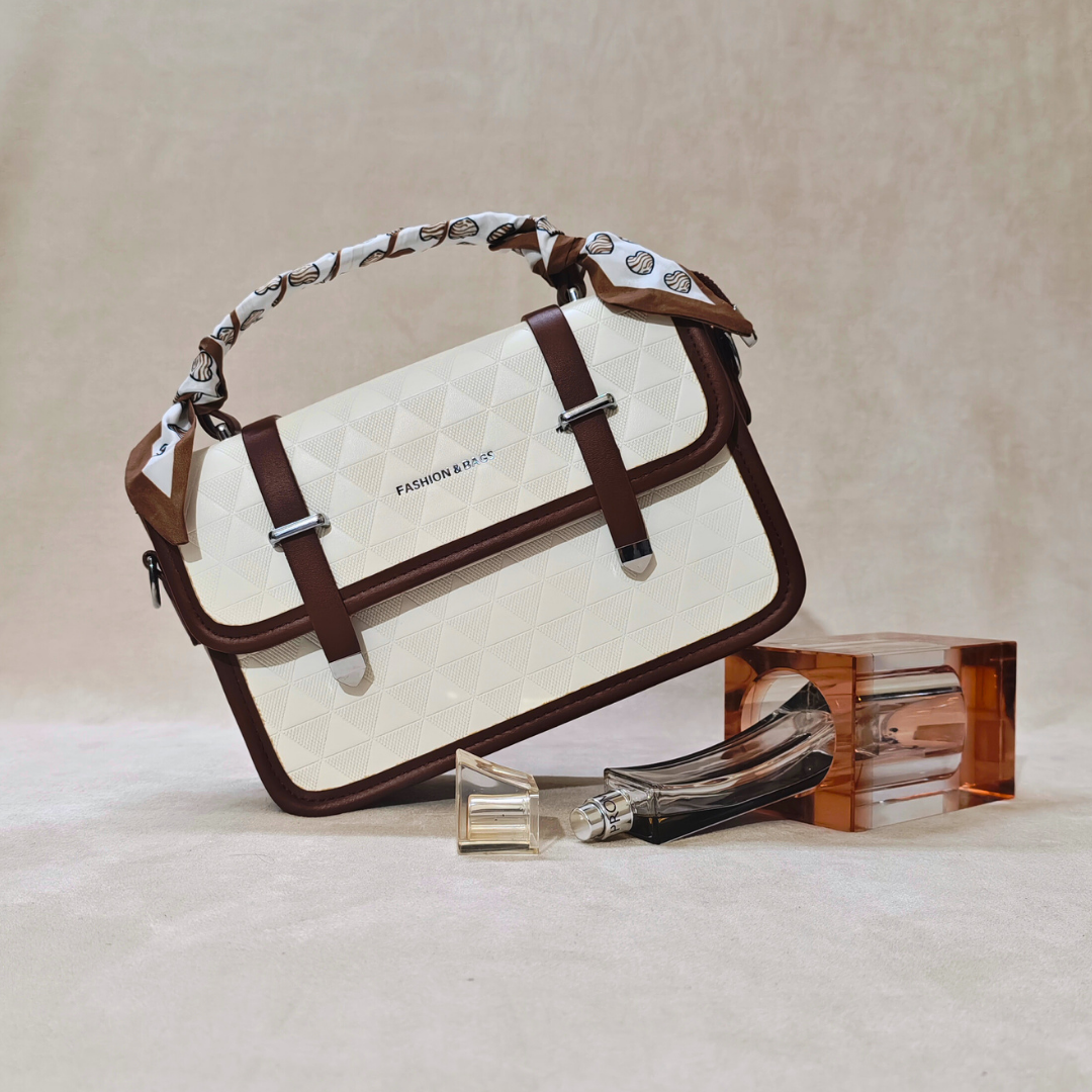 White handbag with brown accents and a scarf, next to perfume bottles on a beige background