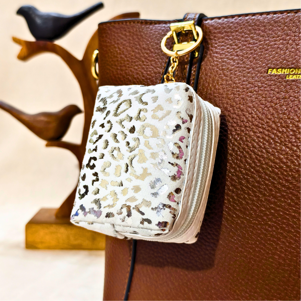 White pouch with leopard print pattern attached to a brown leather handbag.