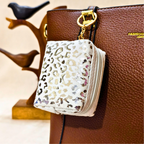 White pouch with leopard print pattern attached to a brown leather handbag.