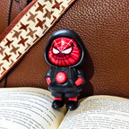 Spider-Man figurine on an open book with a brown leather surface and patterned strap in the background.