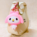 Pink cartoon character keychain attached to a beige handbag.