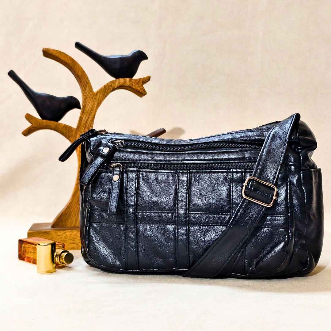 Black leather handbag with a strap on a beige background