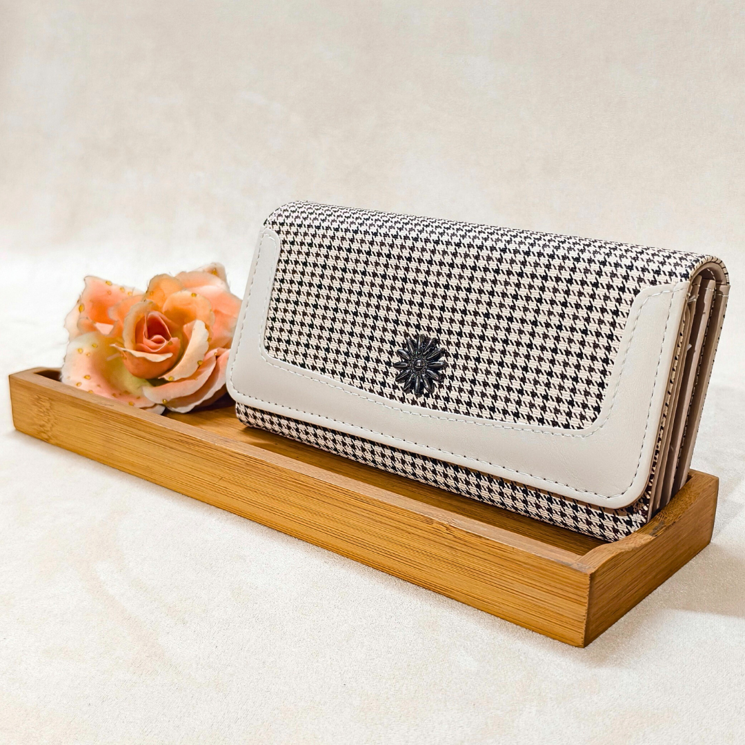 Houndstooth patterned wallet with white accents on a wooden tray with a flower