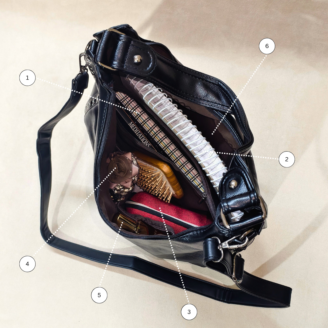 Black leather bag with various items on a beige background