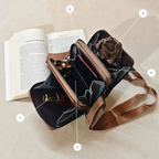 Brown leather handbag with rose detail on a beige surface next to an open book