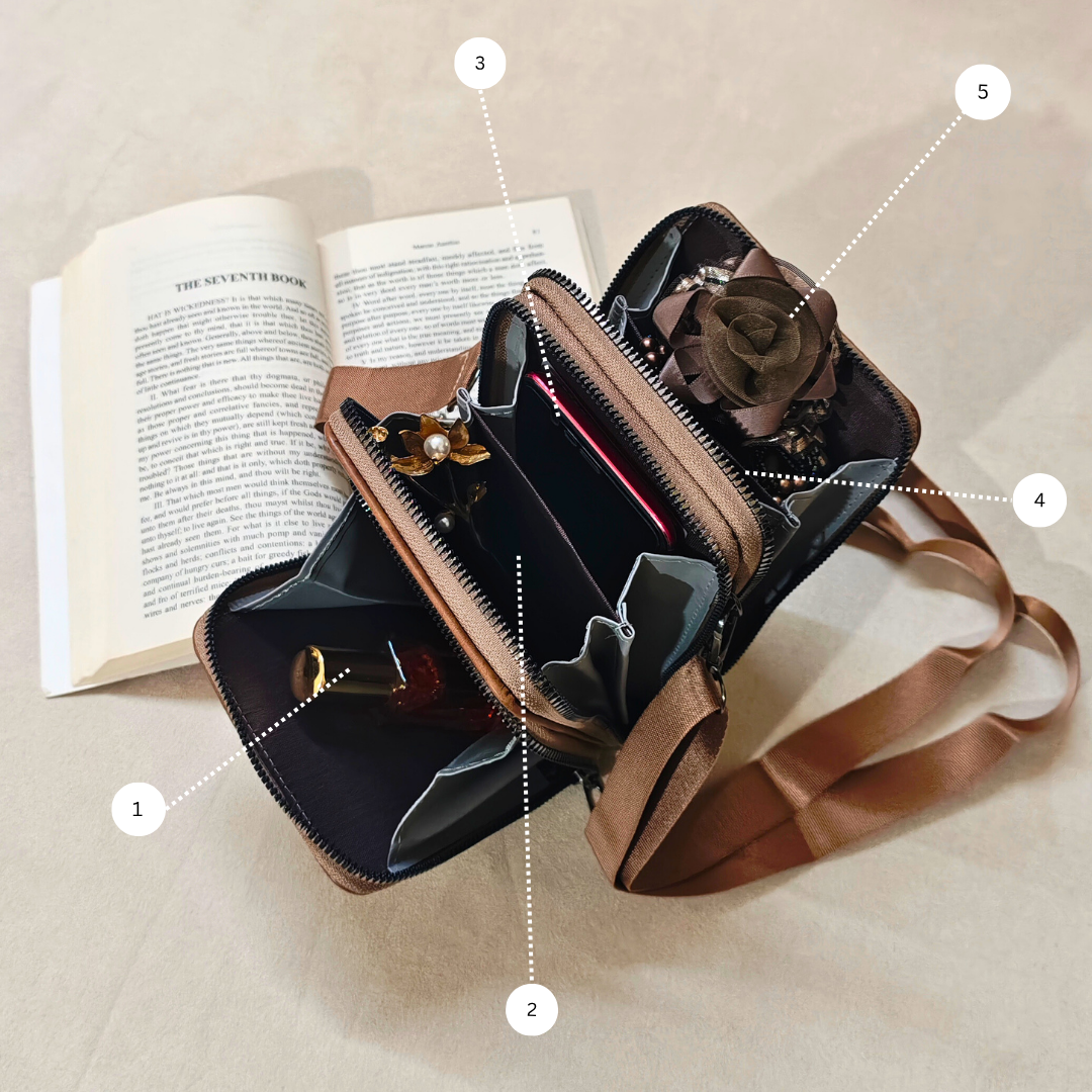 Brown leather handbag with rose detail on a beige surface next to an open book