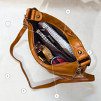 Brown leather bag with compartments labeled on a white background