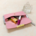 Pink makeup pouch with lipsticks and a brush on a beige surface