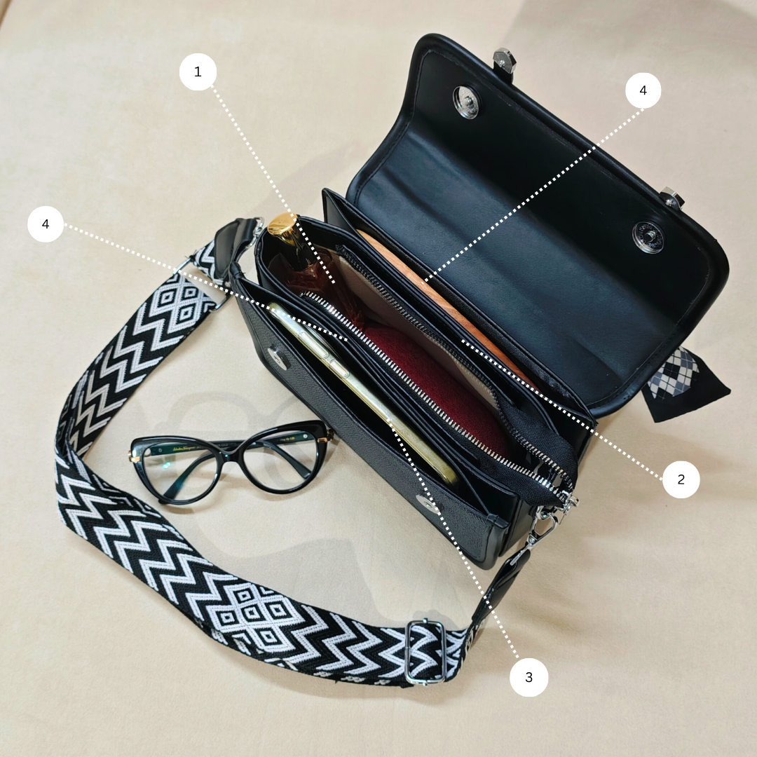 black sling bag with its flap open along side some pair of glasses.