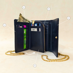 Black wallet with gold chain on a beige background