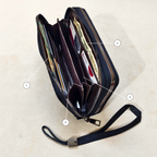 black wallet with an open zip showcasing its compartments with items inside it.