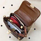 Brown leather handbag with gold accents on a beige background