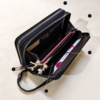 Black handbag with compartments and a strap on a beige background