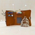 Brown leather wallet with card slots and a glass Buddha statue on a beige background