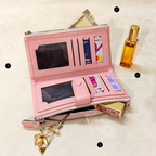 Pink wallet with card slots and a small mirror, next to a gold flower and perfume bottle on a beige background.
