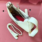 White handbag with a strap on a pink background