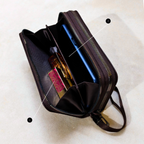 Black travel bag with compartments containing a blue bottle and pink item on a light background