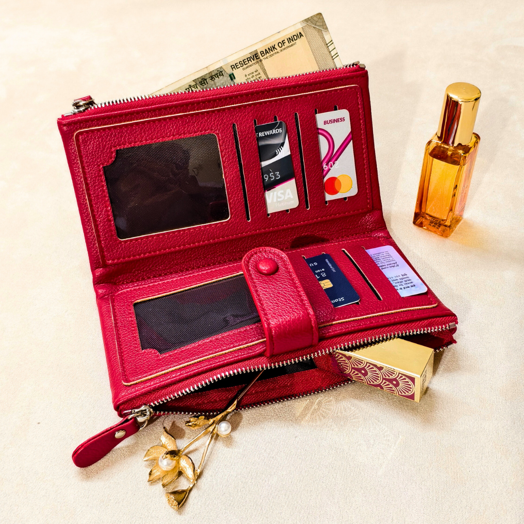Red wallet with card slots and a small mirror, placed on a textured surface with a perfume bottle and money in the background.