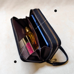 Black travel pouch with compartments containing a bottle and a phone on a beige background