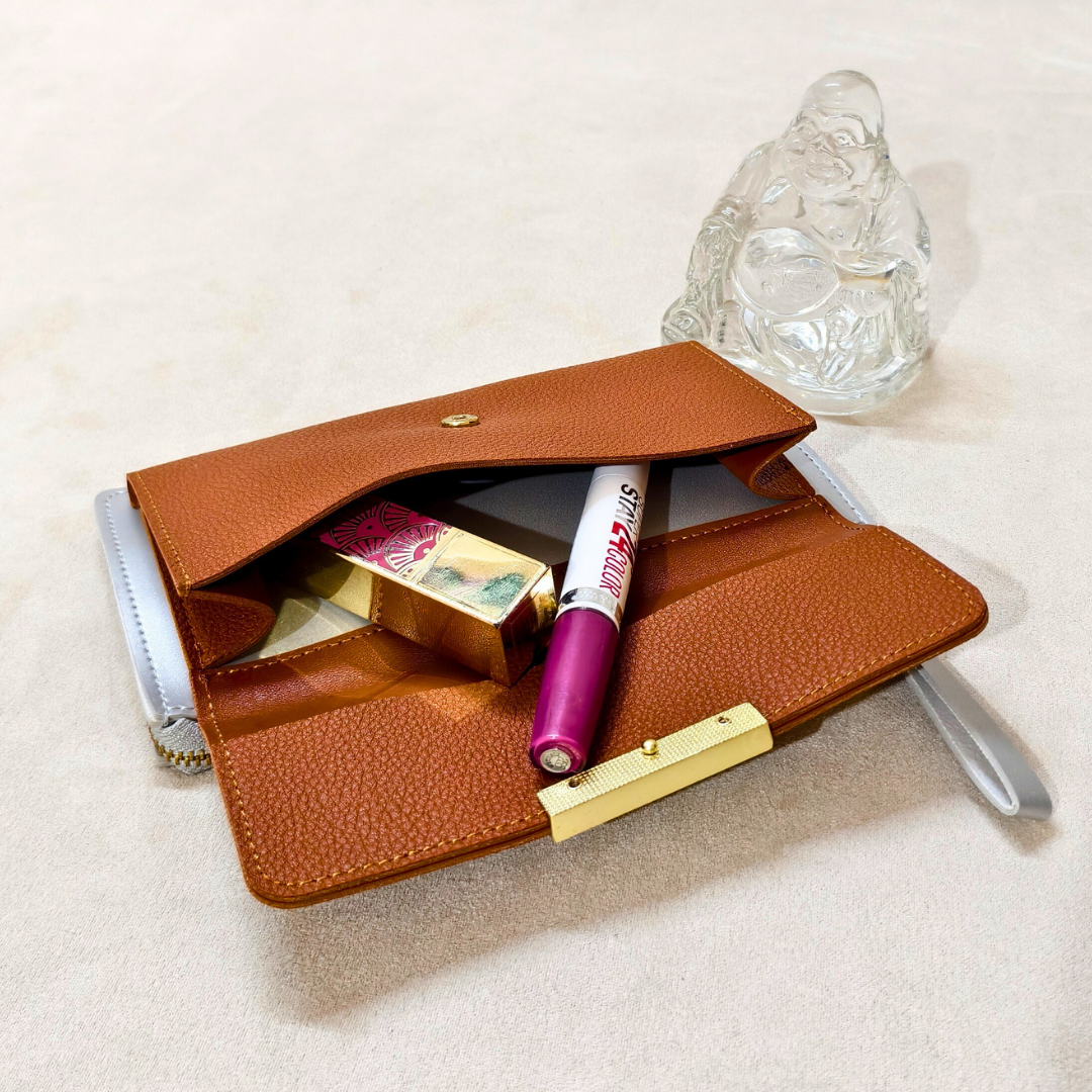 Brown leather wallet with makeup items on a light surface