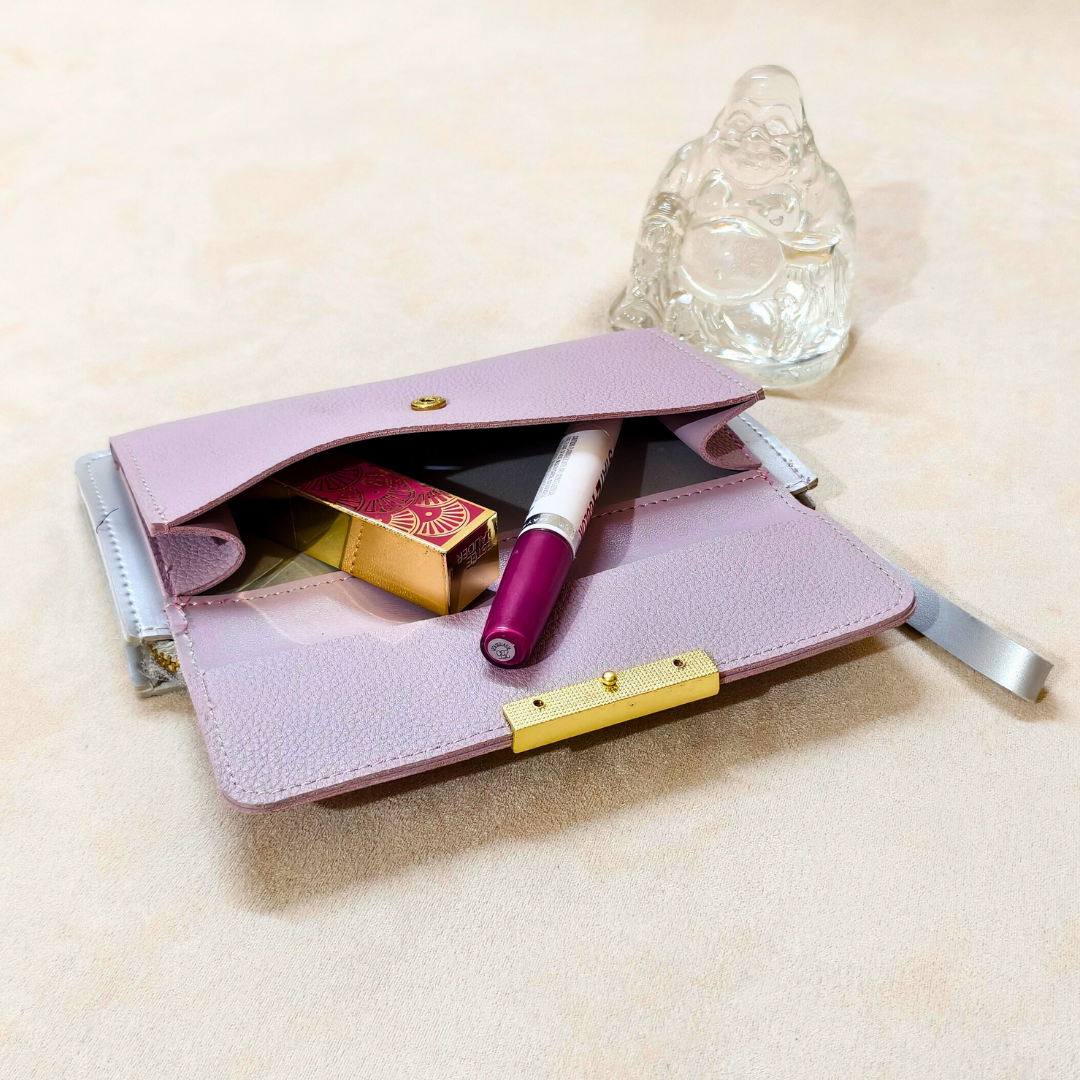 Pink leather wallet with items on a beige surface