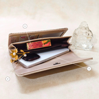 Open beige wallet with phone and cards on a light surface