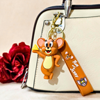 Keychain with cartoon character attached to a bag next to a red rose