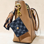 Brown handbag with a blue patterned keychain on a beige background