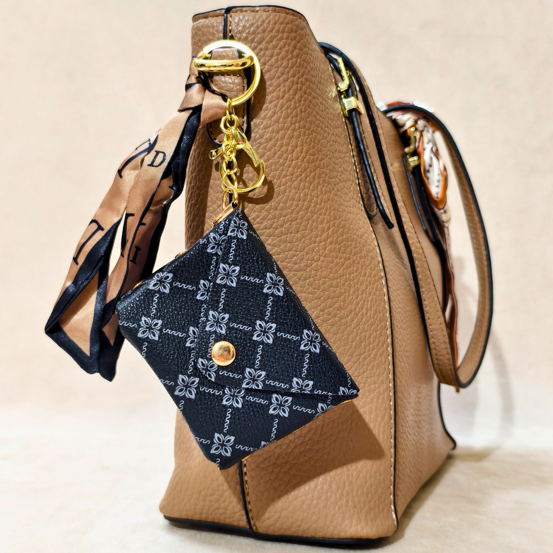 Brown handbag with a blue patterned keychain on a beige background