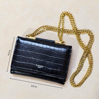 Black crocodile-patterned handbag with gold chain strap on a beige background