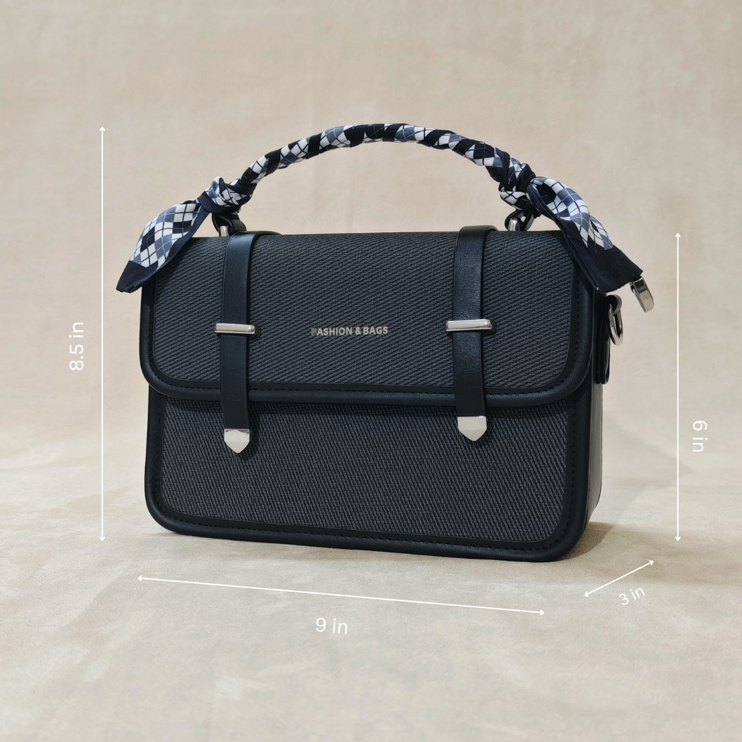 A black sling bag in front of fa beige background tilted over slightly to the left.