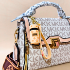 Designer handbag with visible brand logo and keychain on a beige background