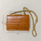 Brown crocodile-patterned handbag with gold chain strap on a light beige background, featuring dimensions.